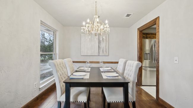 Dining space with dark wood finished floors, baseboards, an inviting chandelier, and visible vents | Image 10