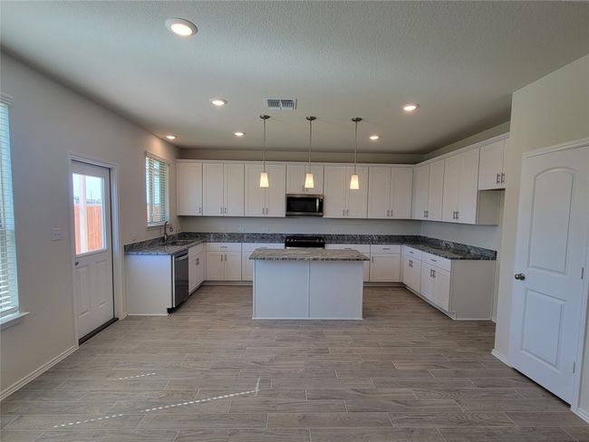 Kitchen with wood tiled floor, white cabinets, visible vents, and stainless steel appliances | Image 6