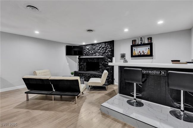 Bar featuring visible vents, a stone fireplace, light wood finished floors, and recessed lighting | Image 18