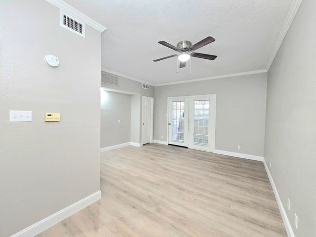 Unfurnished room featuring ceiling fan, light wood-style flooring, ornamental molding, baseboards, and a textured ceiling | Image 5