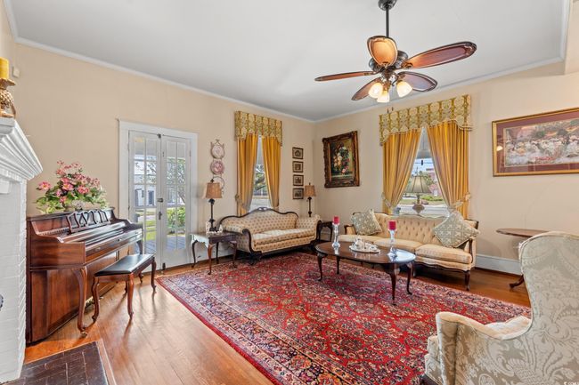 Living room with wood finished floors, crown molding, ceiling fan, and french doors | Image 7