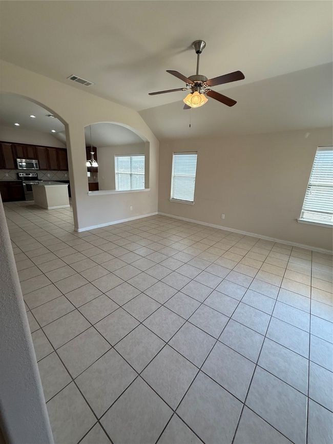 Unfurnished room featuring light tile patterned floors, ceiling fan, arched walkways, visible vents, and baseboards | Image 7