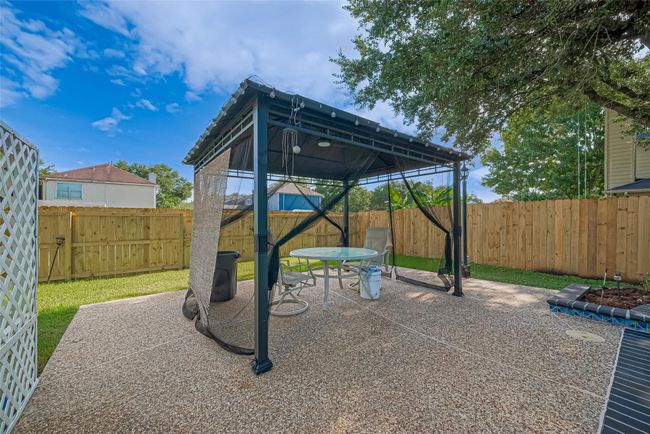 Backyard oasis features a saltwater pool and hot tub, all surrounded by a brand-new perimeter fence. Enjoy outdoor living under the pergola, with plenty of space to relax or entertain. Robotic pool cleaners are included for easy maintenance. Spacious yard extends to the side, perfect for play or gardening. | Image 40