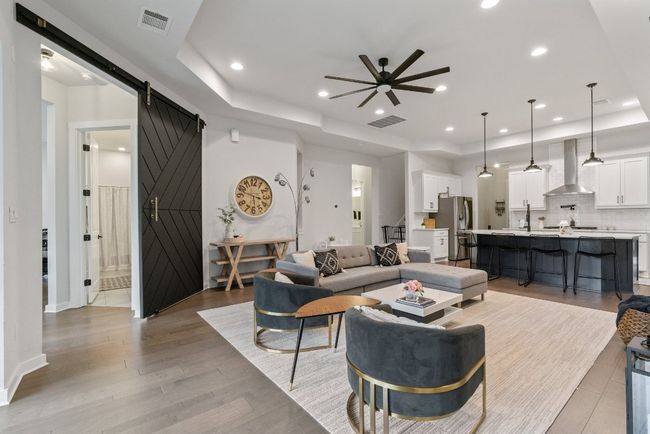 Living room featuring a barn door, a raised ceiling, ceiling fan, light wood-type flooring, and recessed lighting | Image 17
