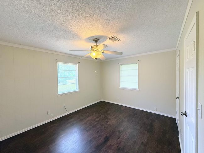 Spare room with dark wood-type flooring, a ceiling fan, ornamental molding, and a textured ceiling | Image 10