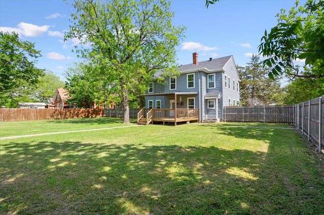 Rear view of house with a fenced backyard, a wooden deck, a lawn, and a chimney | Image 32