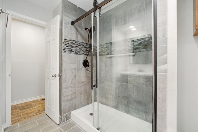 The ensuite bath is beautifully updated with a glass-enclosed shower boasting floor to ceiling custom tile backspash for a touch of spa-like luxury. | Image 23