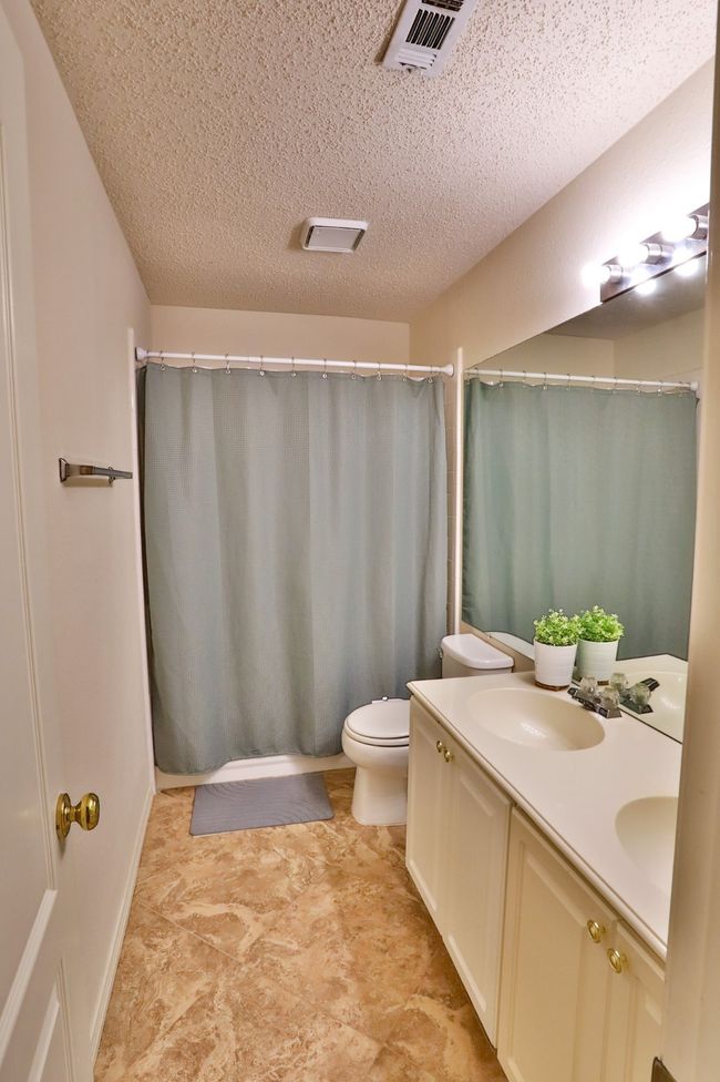 Bathroom featuring double vanity, a textured ceiling, and a shower with shower curtain | Image 21