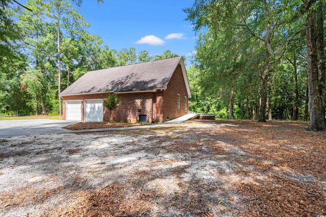 View of property exterior with concrete driveway, brick siding, an attached garage, and a shingled roof | Image 11