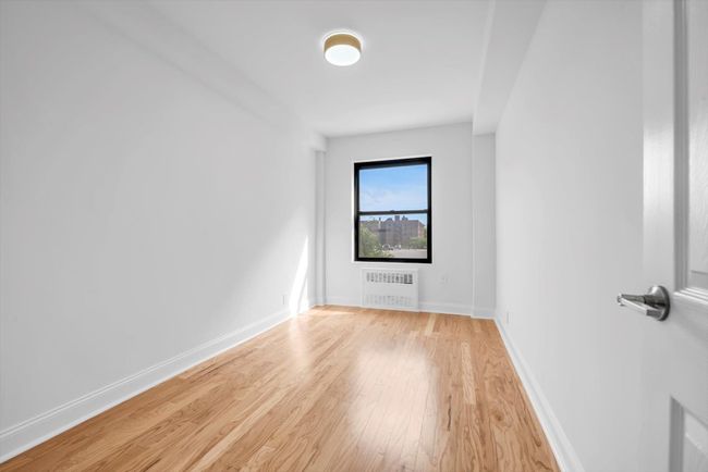 Spare room featuring radiator heating unit and light wood-style flooring | Image 14