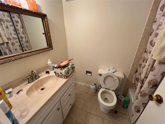 Full bath with vanity, toilet, tile patterned flooring, shower / bathtub combination with curtain, and baseboards | Image 6