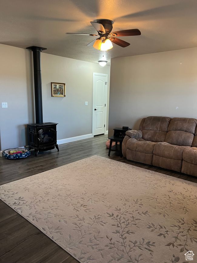 Living room featuring a wood stove, dark wood finished floors, and a ceiling fan | Image 38