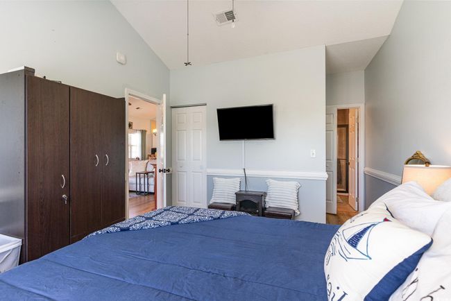 Bedroom with visible vents, connected bathroom, high vaulted ceiling, and wood finished floors | Image 13