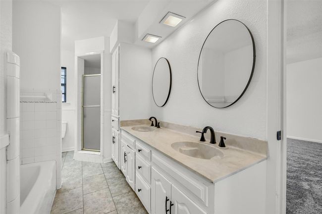 Bathroom featuring double vanity, a shower with shower door, a bathtub, and tile patterned floors | Image 24