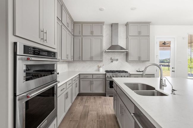 Kitchen with appliances with stainless steel finishes, wall chimney exhaust hood, gray cabinets, and a sink | Image 14