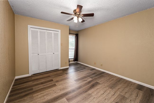 Unfurnished bedroom featuring baseboards, a textured ceiling, and dark wood-type flooring | Image 12