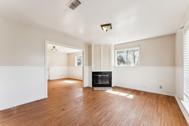 Unfurnished living room with a multi sided fireplace, a wainscoted wall, light wood-style flooring, and visible vents | Image 11