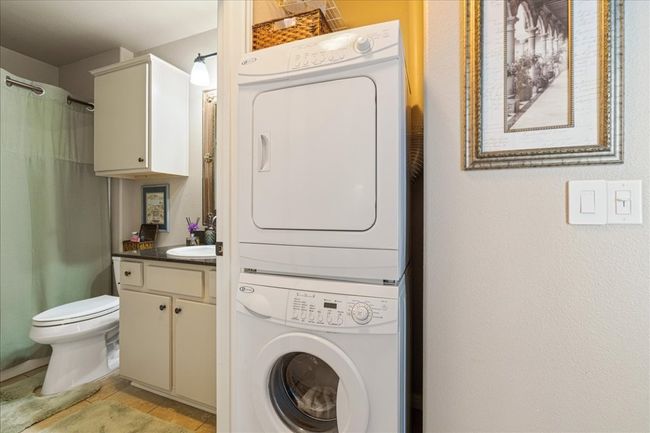 Clothes washing area with stacked washing maching and dryer, laundry area, and a sink | Image 31