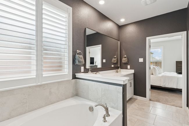 Bathroom with a textured wall, connected bathroom, a bath, vanity, and tile patterned flooring | Image 17