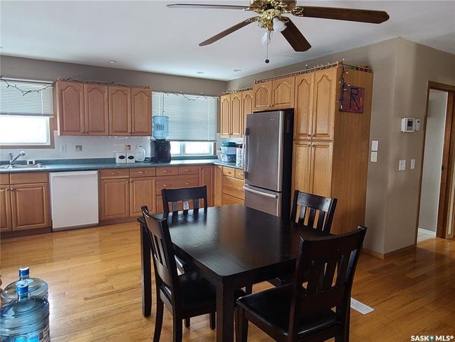 Kitchen with white dishwasher, stainless steel fridge, light wood-type flooring, and tasteful backsplash | Image 10