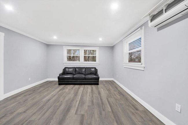 Sitting room with an AC wall unit, healthy amount of natural light, wood finished floors, baseboards, and recessed lighting | Image 4