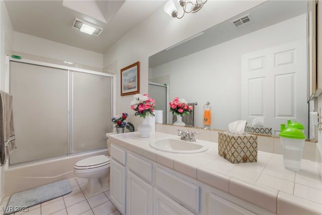 Full bathroom featuring vanity, bath / shower combo with glass door, toilet, visible vents, and tile patterned flooring | Image 29