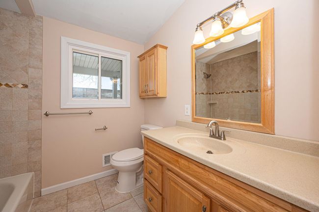 Bathroom with baseboards, visible vents, tile patterned flooring, and shower / bathtub combination | Image 17