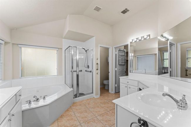 The spacious primary bath offers a spa-like retreat with a deep soaking tub, separate glass-enclosed shower, and expansive vanity with dual sinks and a makeup area. | Image 25