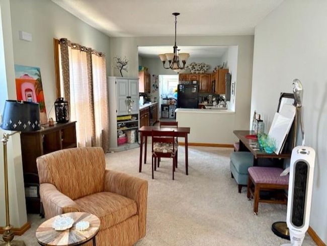 Dining room with baseboards, heating unit, a chandelier, and light carpet | Image 13