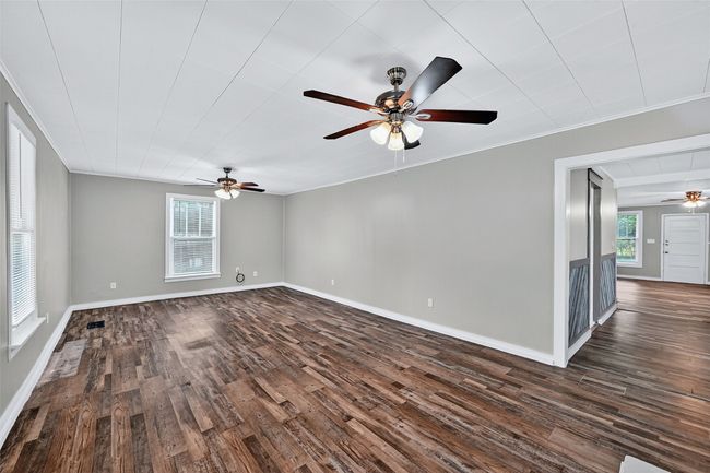 Empty room featuring ceiling fan, dark wood finished floors, and crown molding | Image 5