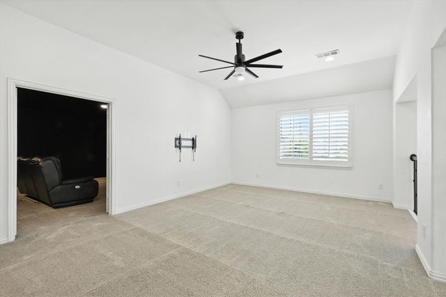 Carpeted spare room featuring a ceiling fan and lofted ceiling | Image 23