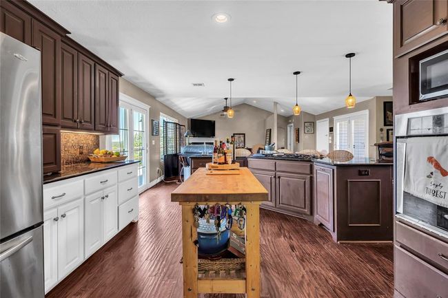 Kitchen featuring appliances with stainless steel finishes, dark wood-type flooring, vaulted ceiling, open floor plan, and plenty of natural light | Image 15