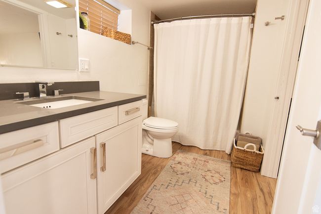 Full bath with toilet, wood finished floors, vanity, and a shower with shower curtain | Image 10