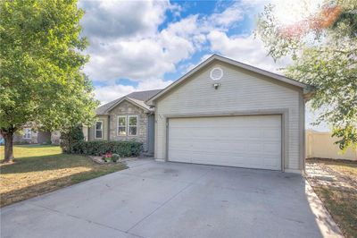 Ranch-style house with a front yard and a garage | Image 1