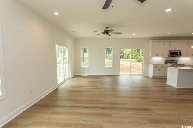 Unfurnished living room featuring a ceiling fan, recessed lighting, healthy amount of natural light, light wood-style floors, and baseboards | Image 11