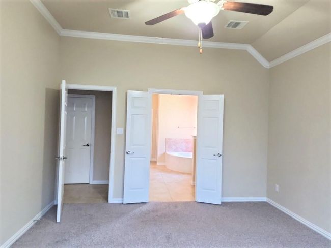 Unfurnished bedroom with crown molding, light carpet, baseboards, lofted ceiling, and a ceiling fan | Image 25