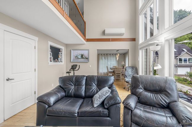 Living area featuring an AC wall unit, a towering ceiling, and wood finished floors | Image 10