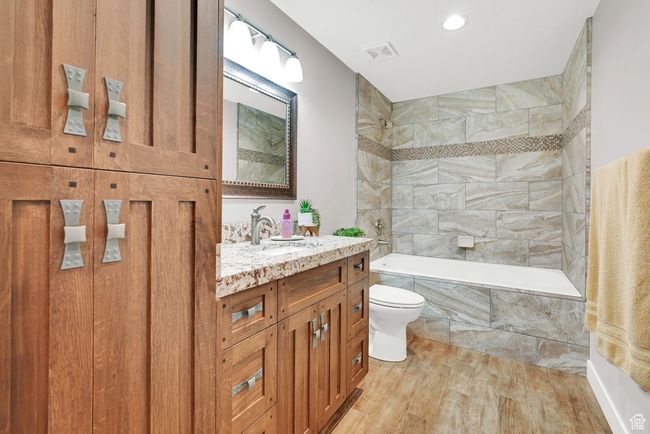 Full bathroom featuring tiled shower / bath combo, vanity, toilet, and hardwood / wood-style flooring | Image 16