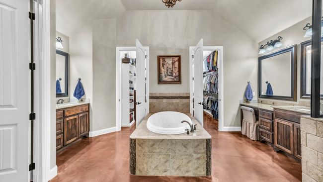 Bathroom with vaulted ceiling, a garden tub, two vanities, and concrete flooring | Image 31