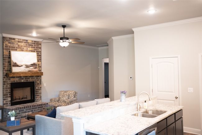 Kitchen with a brick fireplace, ceiling fan, crown molding, and a sink | Image 7