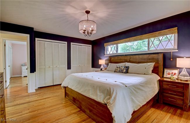 Bedroom with two closets, light wood-type flooring, and a chandelier | Image 24