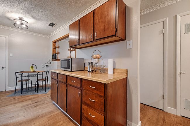 Bank of kitchen cabinets, counter space, and view of dining area. | Image 9