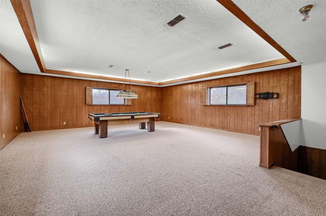 Rec room featuring a textured ceiling, wooden walls, a tray ceiling, billiards, and plenty of natural light | Image 30