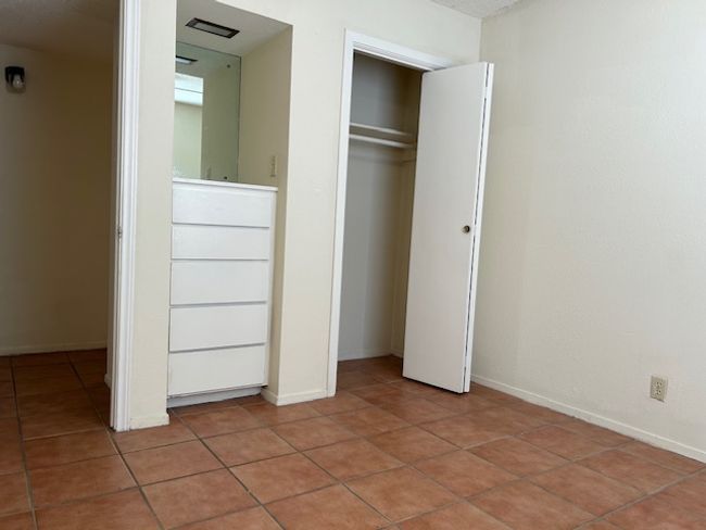 Unfurnished bedroom with light tile patterned flooring, baseboards, and a closet | Image 7