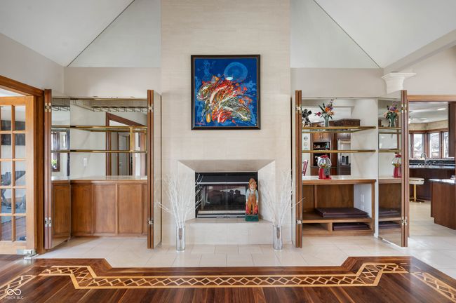 unfurnished living room featuring decorative columns, lofted ceiling, a tiled fireplace, and tile patterned flooring | Image 12