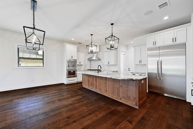 Kitchen with visible vents, an inviting chandelier, stainless steel appliances, wall chimney range hood, and tasteful backsplash | Image 9