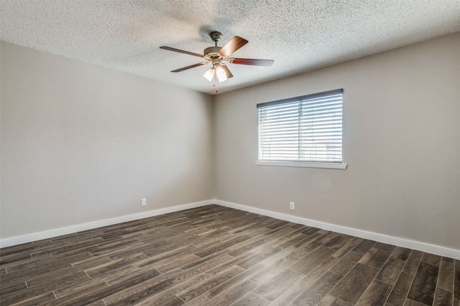 Unfurnished room featuring dark wood finished floors, a ceiling fan, baseboards, and a textured ceiling | Image 11