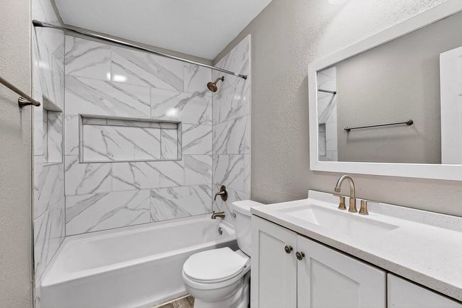 Bathroom featuring a textured wall, vanity, and shower combination | Image 6