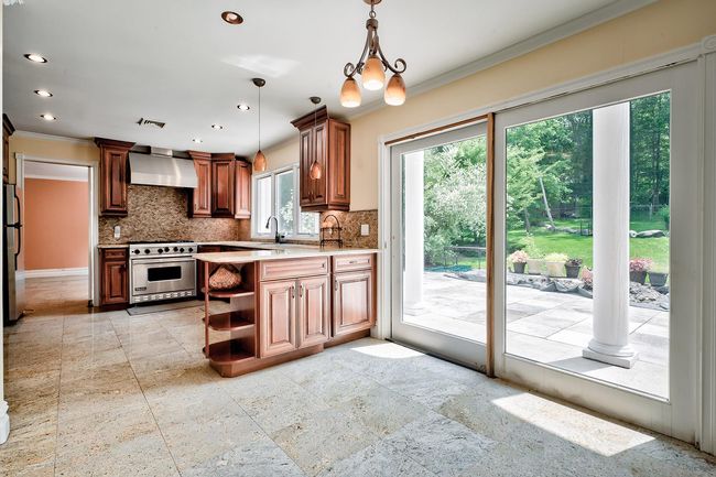 Kitchen featuring open shelves, premium stove, decorative backsplash, and wall chimney range hood | Image 9