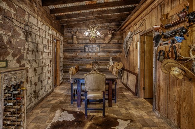 Wine cellar with stone finish floor, wooden walls, beamed ceiling, and a notable chandelier | Image 5